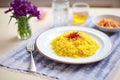 saffron flowers next to a finished plate of risotto milanese