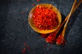 Saffron Spice. Saffron spices on black stone table in a wood bowl and a spoon. Spice and herbs on slate background. Seasonings Royalty Free Stock Photo