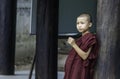 Sagaing/Myanmar-October 2nd 2019: A Burmese novice is leaning against a wooden post in a temple