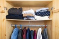 Sagging shelf with lots of clothes in a wood wardrobe. Royalty Free Stock Photo