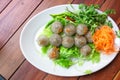 Sago pork and fried garlic toping and chilli served with vegetable on circle white plate, Kanom Saku Sai Moo. selective focus,