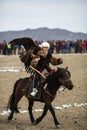 Berkutchi - Kazakh hunter with Golden eagle, while hunting to the hare in desert mountain of Western Mongolia