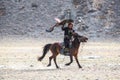 Berkutchi - Kazakh hunter with Golden eagle, while hunting to the hare in desert mountain of Western Mongolia