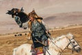 Kazakh Eagle Hunter traditional clothing, while hunting to the hare holding a golden eagle on his arm in desert mountain of Wester Royalty Free Stock Photo