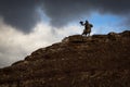 Silhouette of the Eagle Hunter traditional clothing, while hunting to the hare with a golden eagle in desert mountain