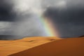 Sahara desert sand dunes with rainbow against dark, cloudy, rainy sky Royalty Free Stock Photo