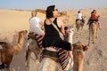 06.11.23 Sahara, Tunisia: Group of tourist ride on camels at sunset in Sahara Desert Tunisia.