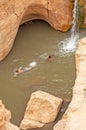 Two young men swim in the water in a narrow gorge in Northern Sahara, Tunisia