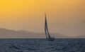 Sail boat in open sea at golden hour in evening. Mountains Silhouette in background