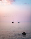 Sail boats at sunset over a glass-like ocean and a colorful sky Royalty Free Stock Photo