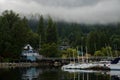 Sail, yachts and motor boats anchor in the harbor. Calm water and the green misty mountains after rain. Deep Cove