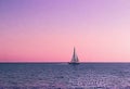 Sailboat in a calm sea during a bright sunset with pink clouds, vacation on a yacht in the ocean Royalty Free Stock Photo