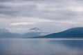 A lone sailboat in vast Norwegian fjord, shrouded peaks loom Royalty Free Stock Photo