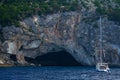 Sailboat in front of Papanikolis Cave Greece sea cliff