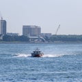 Sailboat gliding through sea against building on the shore