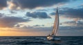 Sailboat Gliding Through Waves at Sunset with Dramatic Clouds in the Ocean Royalty Free Stock Photo