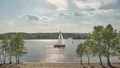 The sailboat goes on the river. Sunny day. Clouds in the blue sky. Vacation on the water. Boat trip. Green trees on the shore. Royalty Free Stock Photo