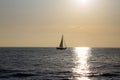 Sailboat on the horizon backlit with the ray of sun setting over the sea Royalty Free Stock Photo