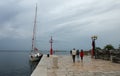 Sailboat, lookout and tourists on pier, cloudy sky and lightho