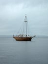 Sailboat with lowered sails in the rain. Antique stylized wooden ship