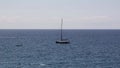 Sailboat lulled by the waves with dinghy moving away on the horizon