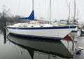 Sailboat moored in boat slip with reflection in still water on a foggy winter morning Royalty Free Stock Photo