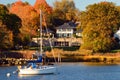 A sailboat is moored off shore of a waterfront mansion