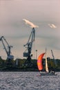 Sailboat moving past the cargo cranes