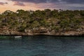 Sailboat moving by rocky cliff on Mediterranean sea in island during sunset