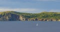 Sailboat navigates near Twillingate cliffs, seascape, landscape, Newfoundland, Atlantic Canada. Royalty Free Stock Photo