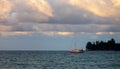 Sailboat over gloomy clouds at sunset Royalty Free Stock Photo