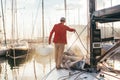 Man washes folded sail on boat or yacht in port