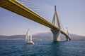 Sailboat passes under the Rio Antirrio Bridge or Charilaos Trikoupis Bridge, photo taken from the boat in summer sunny Royalty Free Stock Photo