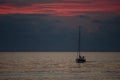 A sailboat returns to the harbor with a very dark cloudy sky in the background at sunset Royalty Free Stock Photo