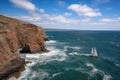 sailboat rounding the point, with dramatic cliff and ocean in the background