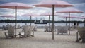 A sailboat sailing with pink beach umbrellas and Muskoka chairs in the foreground Royalty Free Stock Photo