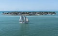 A sailboat sails around a small island.