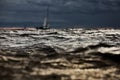 Sailboat in sea at stormy weather, blurred background, stormy clouds sky, sail regatta, reflection of sail in the water Royalty Free Stock Photo