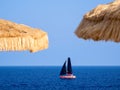 Sailboat on the sea and two straw parasols