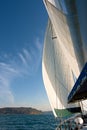 Sailboat at Sea Under Full Sail with Landfall in the distance. Royalty Free Stock Photo