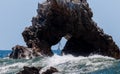 Sailboat seen through hole in arch rock