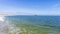 Sailboat seen from a white sand beach on a sunny day