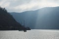 sailboat ship in sea in distance, calm water, sunshine and sun, calm, seascape, in distance mountains and fog