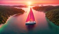 a sailboat with white sails in a calm sea off the coast of a tropical island during a bright sunset, Royalty Free Stock Photo