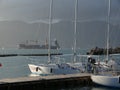 Sailboats anchored at the pier in the Gulf of La Spezia. In the background cargo ship. Sun and clouds