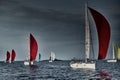 Sailboats compete in a sailing regatta at sunset, sailing race, reflection of sails on water, multi-colored spinaker