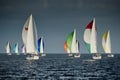 Sailboats compete in a sailing regatta at sunset, sailing race, reflection of sails on water, multi-colored spinaker