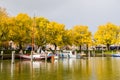 Sailboats at jetty in marina, trees in autumn colours and storm clouds, Enkhuizen, Netherlands