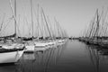 Sailboats in a peaceful harbor with reflections in the calm water. The power of black and white. Royalty Free Stock Photo