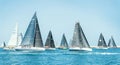 Sailboats races in regatta near Brindisi under blue cloudless sky. Boats have white and black sails